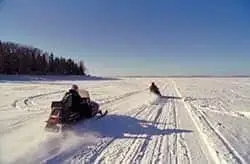 Snowmobilers riding across an open snow-covered flat