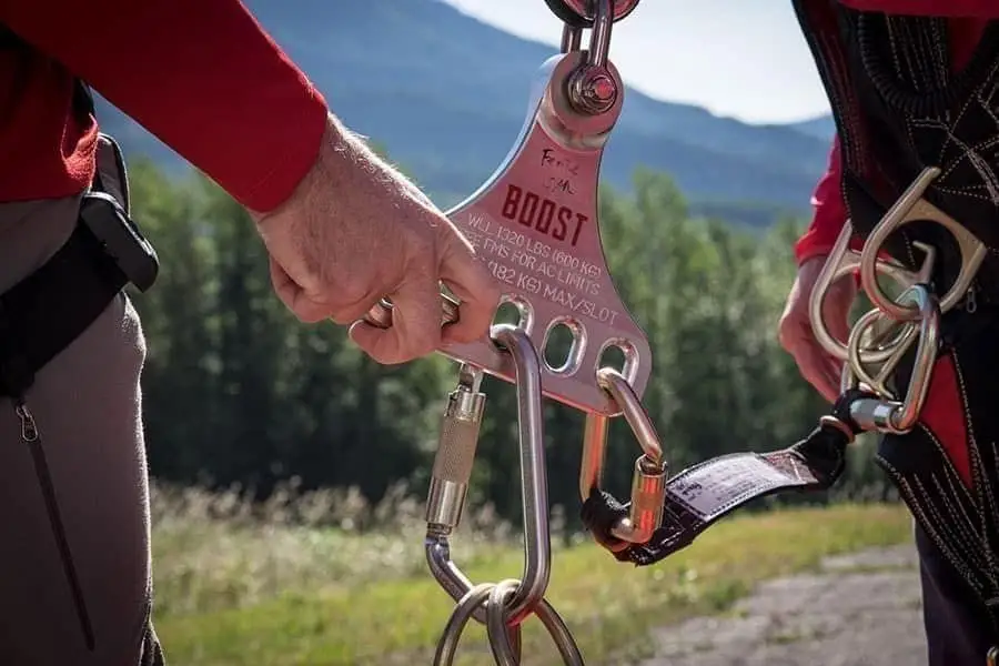 Two members clipping carabiners into a rope-rescue plate during training